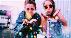 teenaged girls blowing confetti at the camera